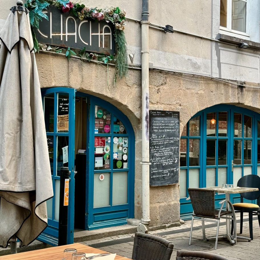 Terrasse et entrée du lieu Aperçu de la terrasse avec ses tables et parasols ainsi que la porte d'entrée